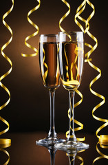 glasses of champagne and streamer on brown background