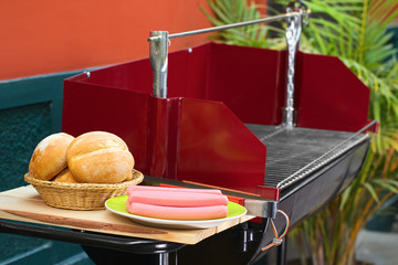 Würstchen und Brotkorb mit Brötchen am Grillgerät