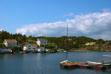 Fototapeta na wymiar Anlegestelle mit Segelboot und weiße Häuser in Lyngor, Norwegen