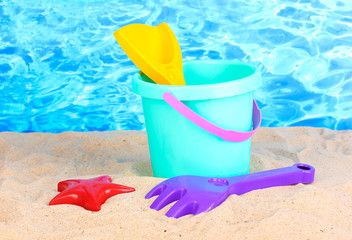 Children's beach toys on sand on water background