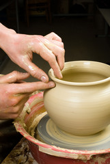 hands of a potter, creating an earthen jar of white clay