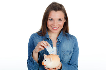 brünette junge frau wirft 20 euro ins sparschwein