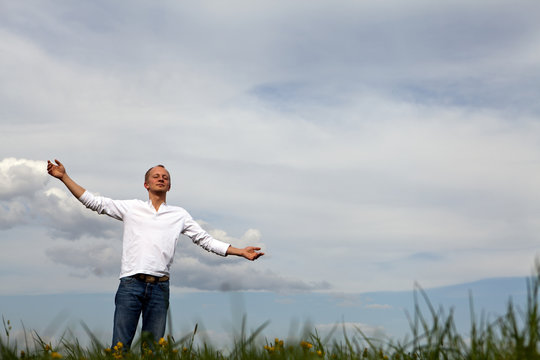 man is standing outside in spring with arms wide open