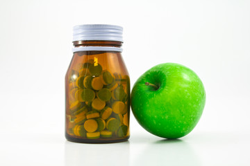 Medicine glass bottle with pills and apple