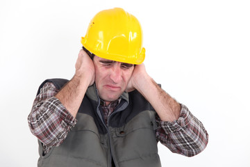 Construction worker holding his hands over his ears