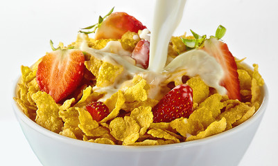 pouring milk in a cornflakes bowl with strawberries. isolated