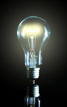 Glowing light bulb over a black background