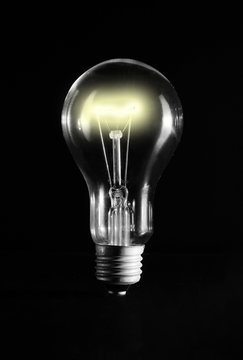 Glowing light bulb over a black background