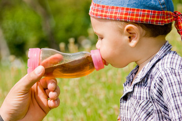 Obraz premium Beautiful boy drinking from plastic bottle