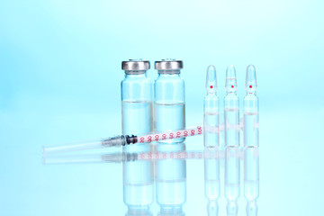 Syringe and medical ampoules on blue background