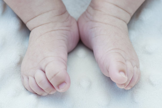 Detail newborn feet on a soft white blanket