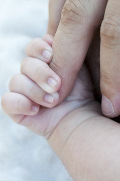 Baby hand grabbing the toe of his father
