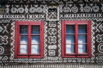 Red windows on wooden wall of traditional cottage