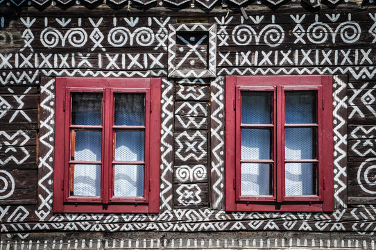 Red windows on wooden wall of traditional cottage