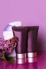 Bottles of cosmetics with lilac flowers