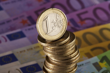 schiefer Münzstapel steht auf Euro Scheinen