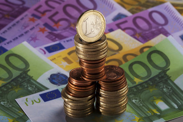wackelige Münzstapel stehen auf Euro Scheinen