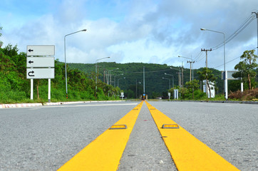 Yellow line on road to moutain with traffic sign