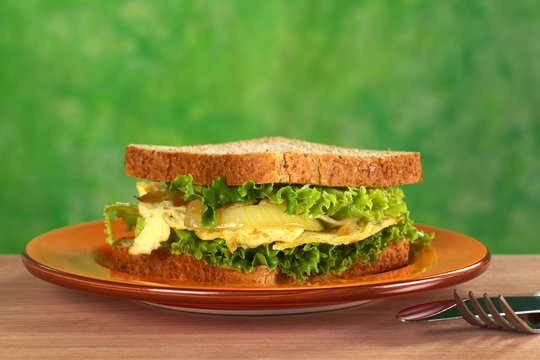 Scrambled eggs sandwich with fried onions and lettuce
