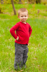 Cute smiling little boy standing in the middle of the meadow