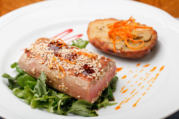 Fried tuna steak and potatoes on the plate