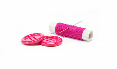 Reel of thread with a needle and buttons on a white background.