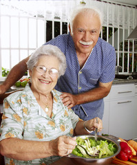 Señores abuelos cocinando en una cocina.Comiendo ensalada.