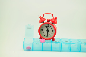 Pill box and red clock show medicine time