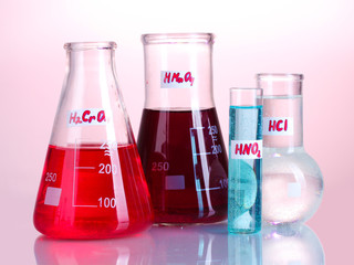 Test-tubes with various acids and chemicals on pink background