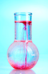 brightly ink in a flask with water on blue background