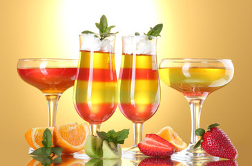 fruit jelly in glasses and fruits on yellow background