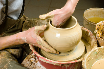 hands of a potter, creating an earthen jar of white clay