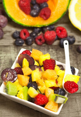 delicious fruit salad with red fruits in a ceramic bowl