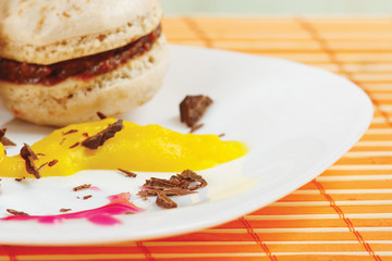 Macaroons and syrup with chocolate on a bamboo table cloth