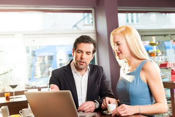 Working colleagues - a man and a woman - sitting in cafe