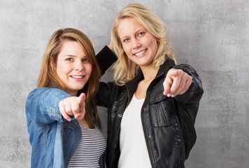 Glückliche jungen Frauen zeigen auf dich
