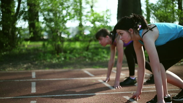 Two young beautiful women running on track lane, dolly shot