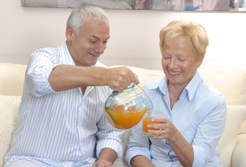 Pareja adulta bebiendo jugo de naranja en casa.