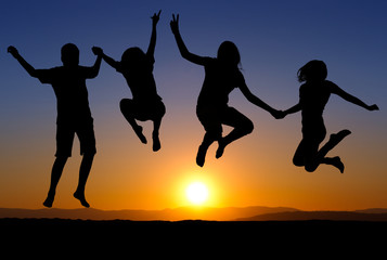 Fototapeta na wymiar silhouette of kids jumping on beach in sunset