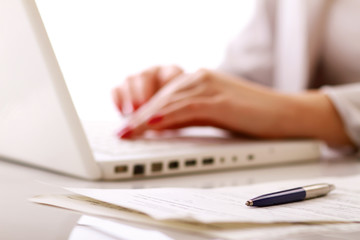 Close-up of woman typing documents on keyboard of laptop.