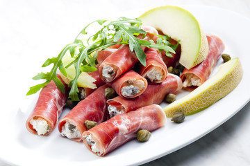 Parma ham rolls filled with cream cheese, Galia melon and capers