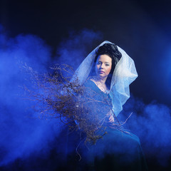 Fototapeta premium girl in medieval dress with bunch of sticks in smoke
