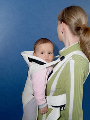 Женщина держит ребенка в слинге, вид сбоку