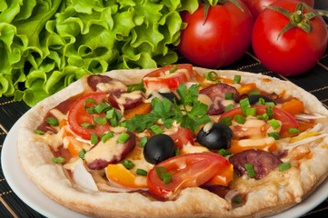 Closeup of pizza with tomatoes, cheese, black olives and peppers