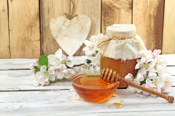Honey in a glass jar and flower on a wooden table