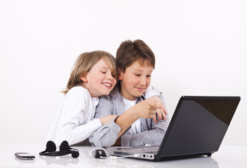 Two cheerful boys looking something on lap top