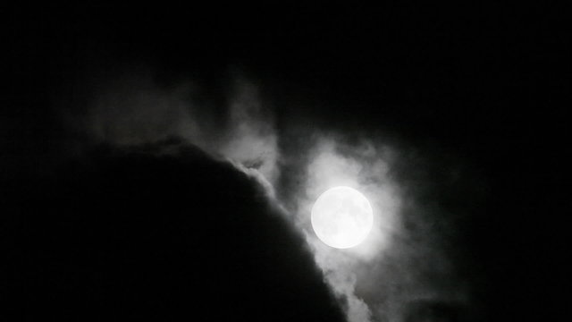 Super moon moving in and out clouds