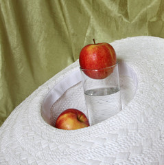 Two apples and water glass in a hat