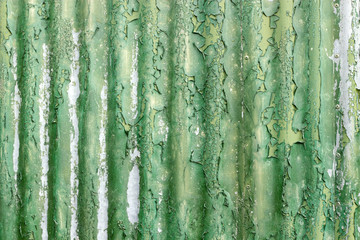 Flaky green paint on weathered corrugated iron.