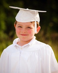 Young boy with cap and gown for preschool graduation